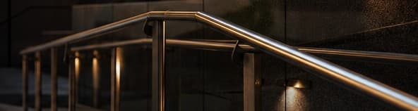 A lit metal handrail along a building walkway after dark