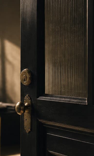 A dark wood office door with brass hardware, warm daylight beyond