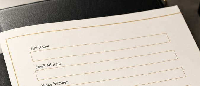 A blank printed inquiry form on ivory paper resting on a black leather folio