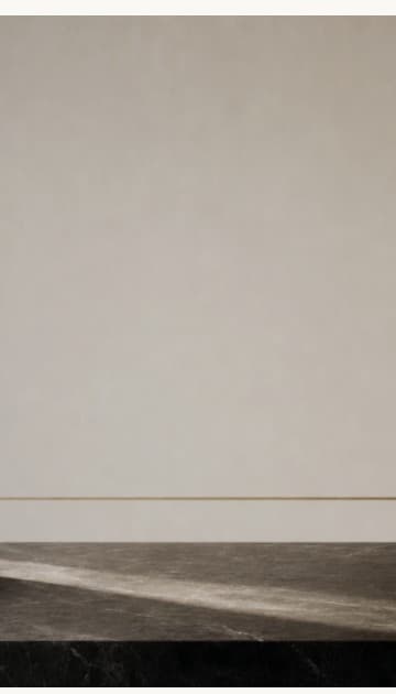 A quiet plaster wall with a fine brass inlay meeting a dark marble ledge