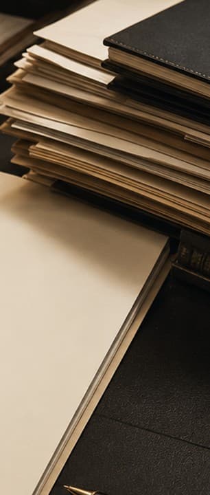 Tall stacks of paper files and folders gathered on a dark desk